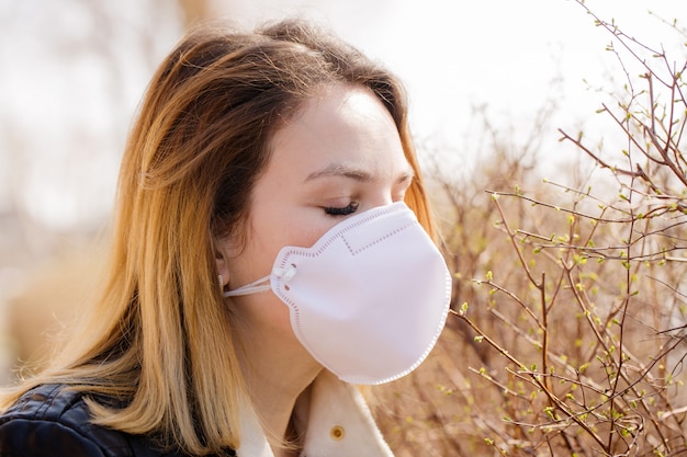 La donna cerca di annusare l'odore della primavera in una maschera protettiva