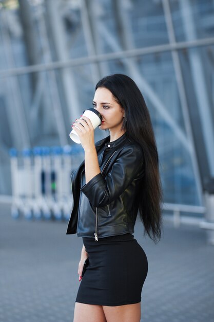 La donna che cammina sulla strada con porta via il caffè