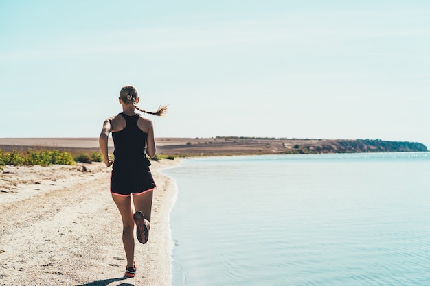 La donna che fa jogging lungo la costa del mare