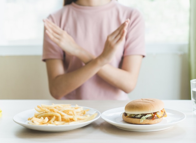 La donna che fa le braccia incrociate firma per rifiutare il junk food (hamburger e patate fritte) che hanno ma