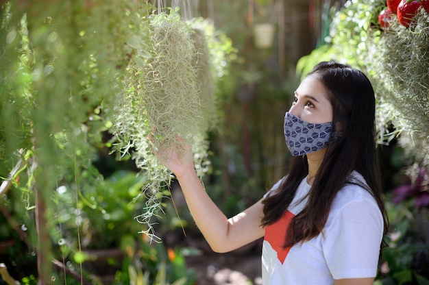 La donna che indossa una maschera sceglie di comprare alberi nel giardino.