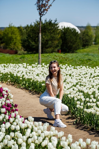 La donna che ride si gira e guarda la telecamera camminando tra tulipani e tavoli da picnic