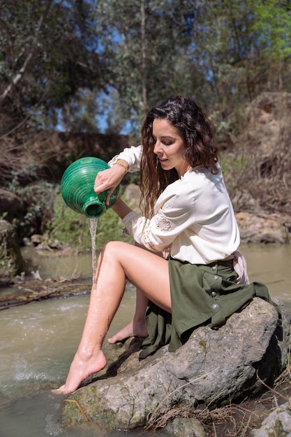 La donna che si lava sulla riva del fiume usa la sua brocca verde