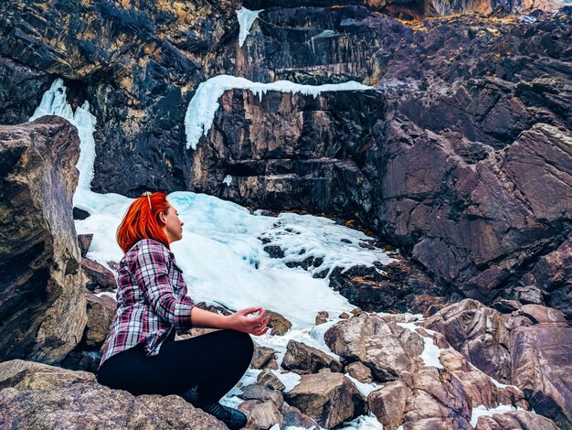 La donna che si siede sulla montagna di roccia. Pratica della donna di yoga sul picco di montagna.