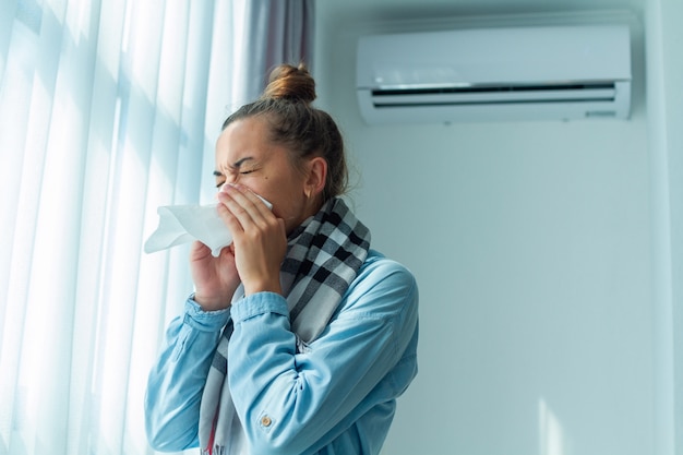 La donna che starnutisce ha preso un raffreddore dal condizionatore d'aria a casa. Malattia del condizionatore