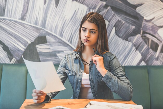 La donna che tiene un giornale al tavolo in un caffè