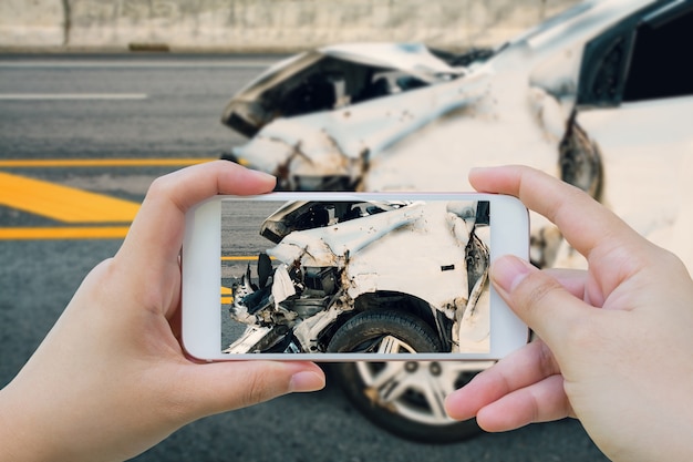 La donna che utilizza lo smartphone scatta foto di un incidente stradale sulla strada