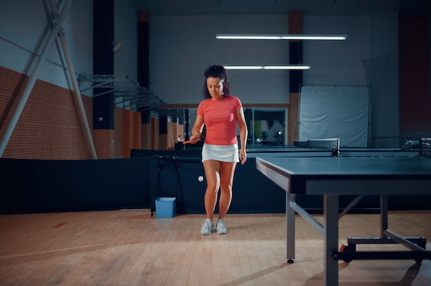 La donna colpisce una palla, tennis da tavolo allenamento in palestra