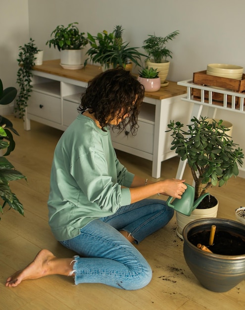 La donna coltiva piante in vaso a casa annaffiando e si prende cura dei fiori giardinaggio e cura delle piante d'appartamento conce