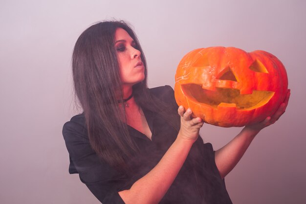 La donna come strega è in piedi con la zucca Halloween e il concetto di carnevale.