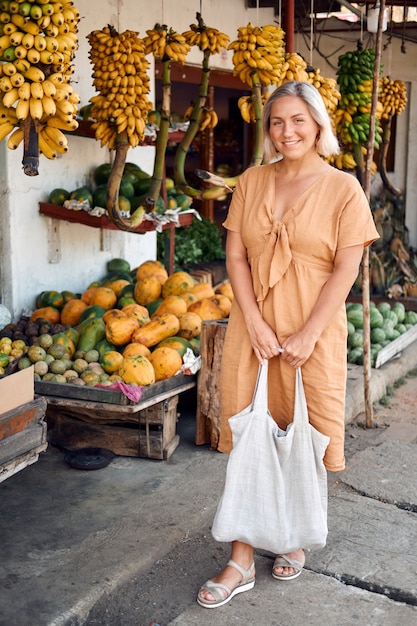 La donna compra frutta fresca al mercato locale esotico