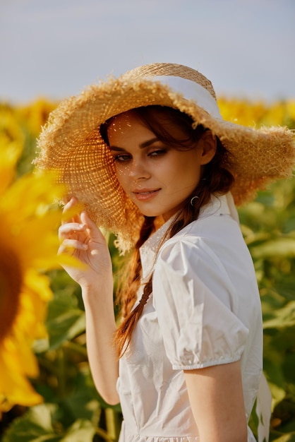 La donna con due trecce cammina attraverso un campo di girasoli in estate