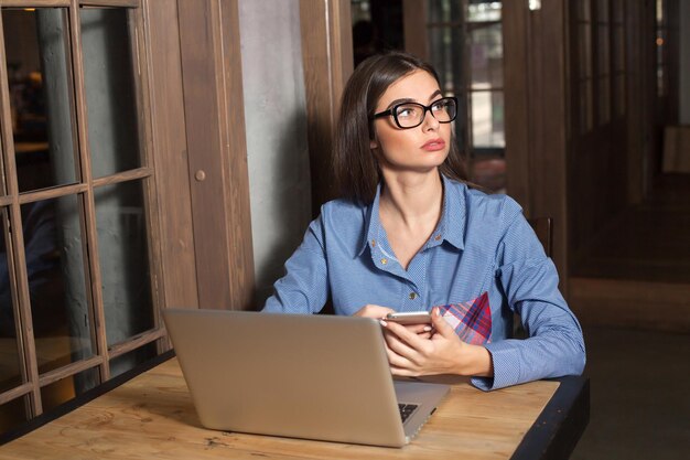 La donna con gli occhiali con laptop e telefono sta lavorando