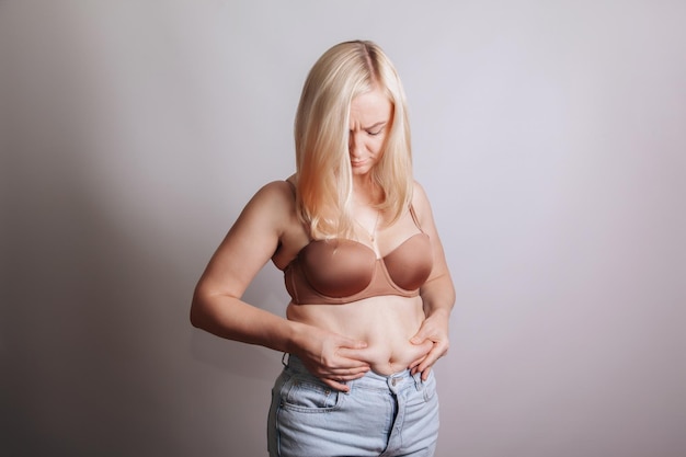 La donna con i capelli biondi si stringe il grasso della pancia sullo stomaco