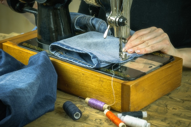 La donna con il maglione nero lavora su una vecchia macchina da cucire.