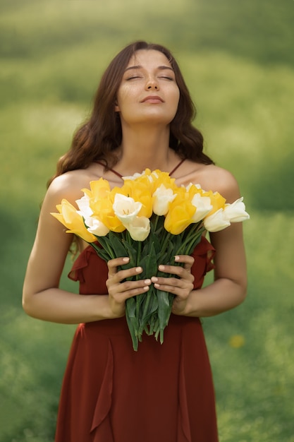 La donna con il mazzo della primavera fiorisce all'aperto