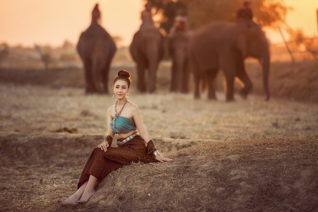 La donna con il vestito tailandese tradizionale abbraccia il suo elefante, al villaggio dell'elefante, Surin, Tailandia