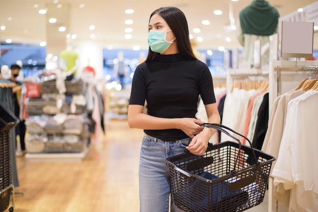 La donna con la maschera facciale sta acquistando i vestiti nel centro commerciale