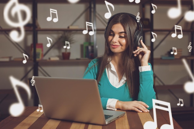 La donna con le cuffie è seduta al tavolo con il laptop