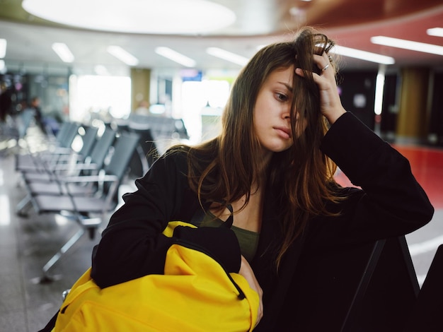 La donna con lo zaino giallo si siede all'aeroporto in attesa di un volo
