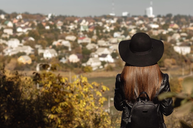 La donna con lo zaino sta guardando la città nel giorno d'autunno