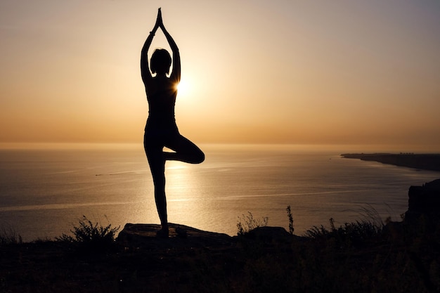 La donna con postura yoga sulla montagna al tramonto.