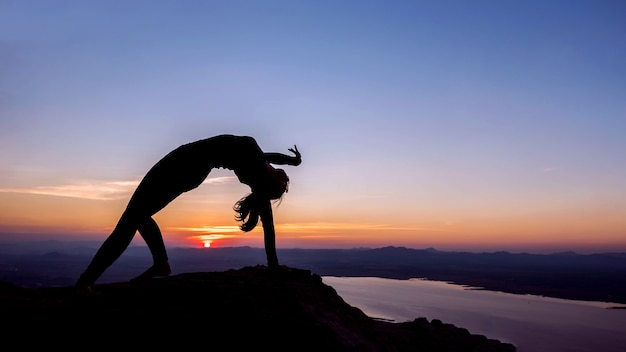 La donna con postura yoga sulla montagna al tramonto.