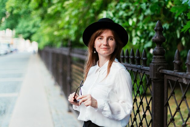 La donna con un cappello cammina vicino al parco