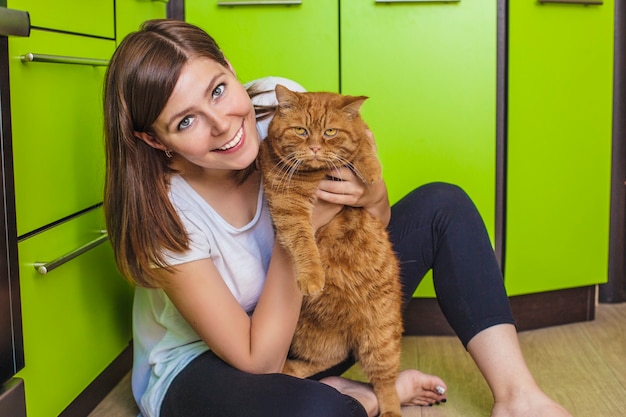 La donna con un gatto rosso tra le braccia che si coccola nella luminosa cucina