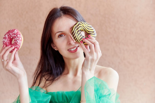 La donna con un trucco luminoso tiene ciambelle colorate Concetto della Giornata nazionale delle ciambelle Vibrante fotografia estiva