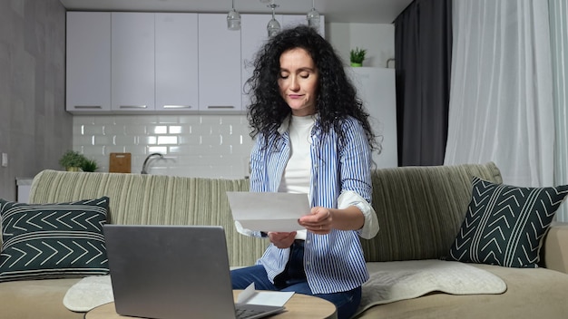 La donna controlla le bollette e inserisce le informazioni nel laptop