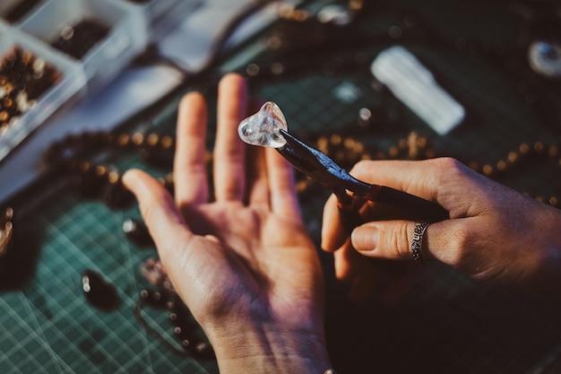 La donna creativa tiene in mano una pinza e un quarzo cristallino.