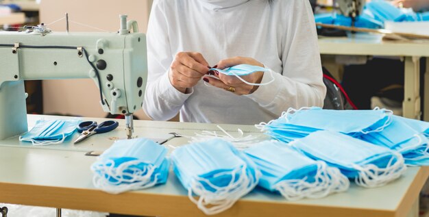 La donna cuce il medico facciale alla macchina per cucire. Pandemia da coronavirus.