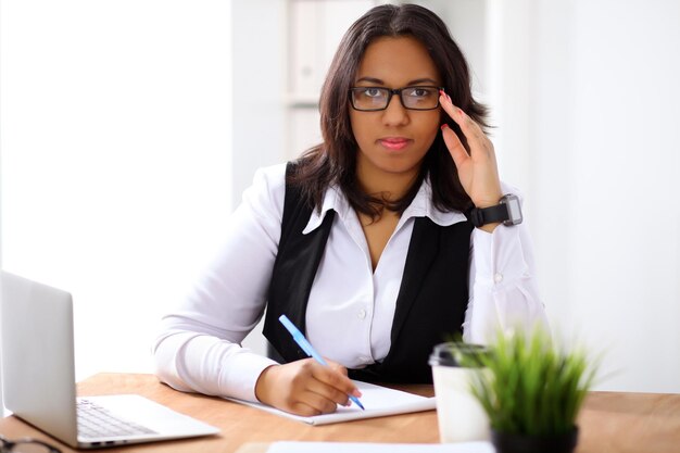 La donna d'affari afroamericana è impegnata con il lavoro di carta in ufficio mentre il sole splende all'aperto