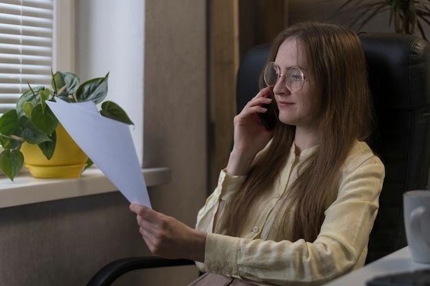 La donna d'affari con gli occhiali sta studiando seriamente i documenti. Esamina il contratto prima di fare un affare