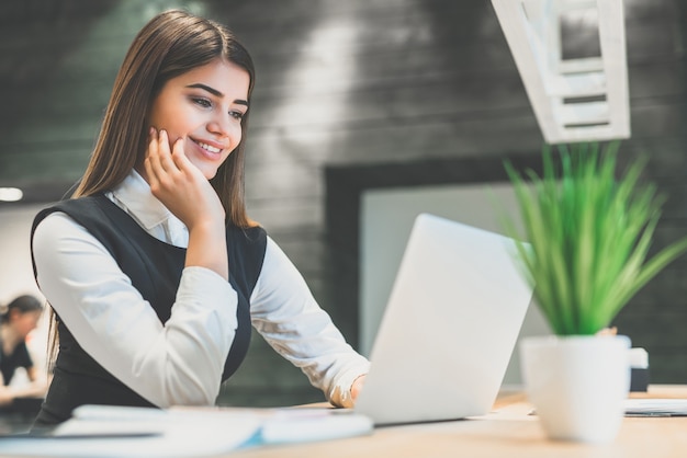 La donna d'affari con un laptop seduta alla scrivania