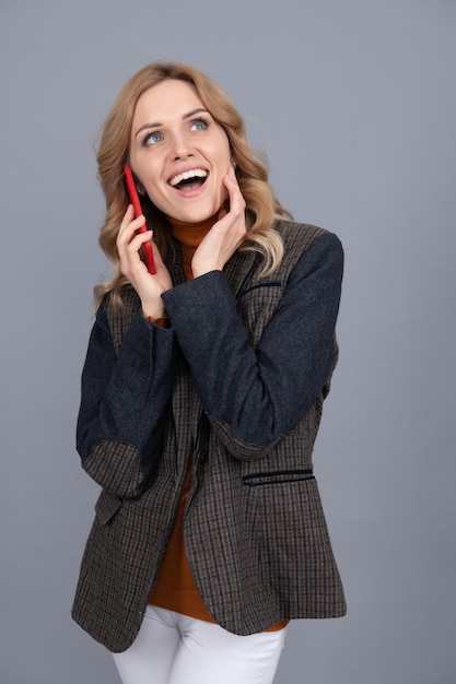 La donna d'affari felice in giacca inglese a scacchi parla sulla comunicazione telefonica
