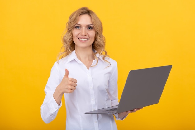 La donna d'affari felice lavora online con il laptop su sfondo giallo che mostra il pollice in alto nella vita moderna