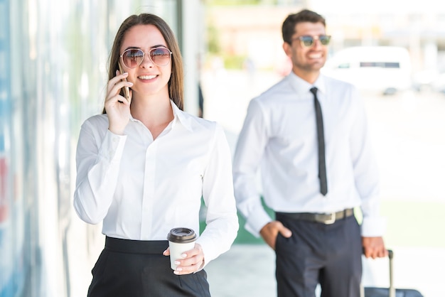 La donna d'affari felice tiene una tazza di caffè e un telefono vicino all'uomo