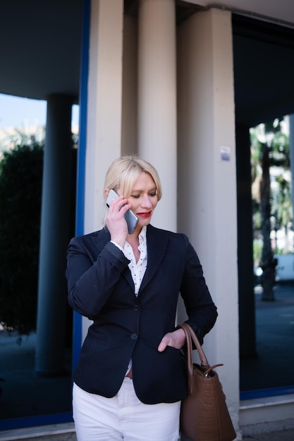 La donna d'affari più anziana parla di affari con il telefono cellulare all'esterno