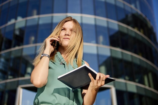 La donna d'affari prende un appuntamento per telefono all'aperto in movimento