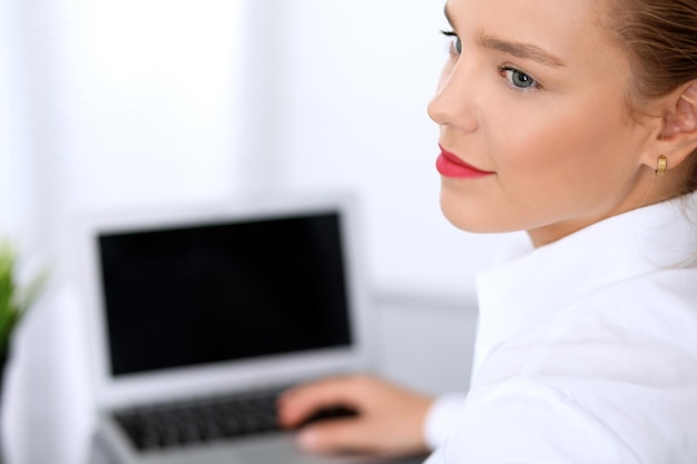 La donna d'affari sta scrivendo sul computer portatile. Contabile o ispettore finanziario femminile che fa rapporto, calcola o controlla l'equilibrio.