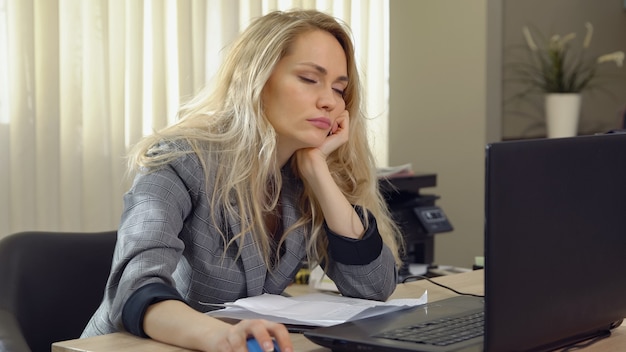 La donna d'affari stanca si addormenta sul posto di lavoro in ufficio.