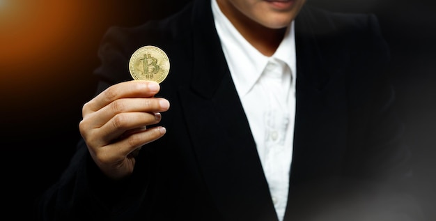 La donna d'affari tiene in mano la moneta reale della criptovaluta Bitcoin per presentare la libertà o lo spazio di copia del mockup della finanza decentralizzata su sfondo nero