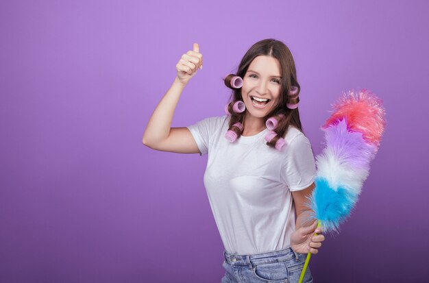 La donna dai capelli castani dagli occhi verdi in bigodini rosa ride sullo sfondo.