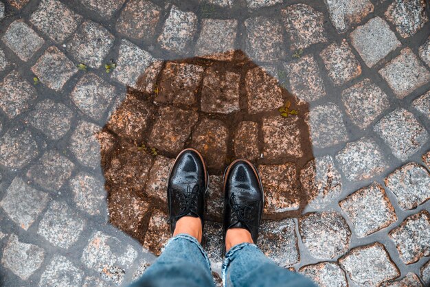 La donna dal punto di vista in prima persona entra nella pozzanghera con le scarpe nere L'autunno sta arrivando