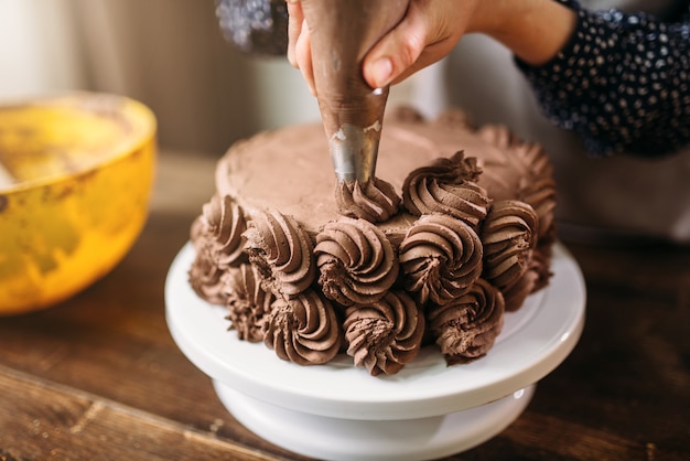 La donna decora la torta con la siringa culinaria