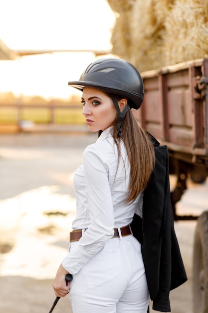 La donna del cavaliere con il casco si trova vicino alle stalle