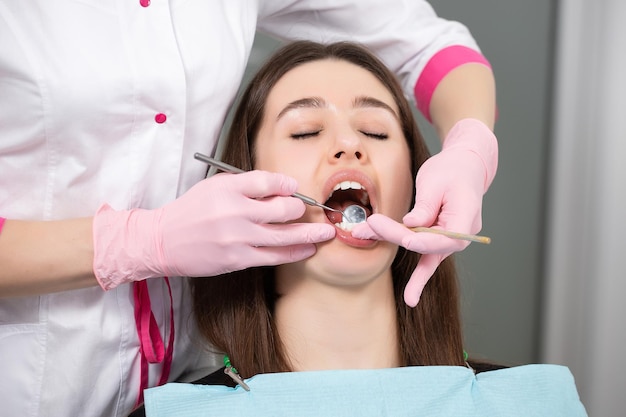 La donna del dentista esamina i denti di un paziente sulla sedia del dentista in una clinica moderna e luminosa.