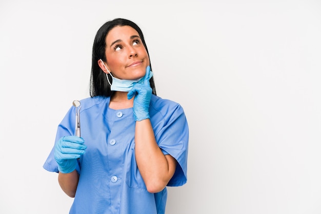 La donna del dentista isolata sulla parete bianca si è rilassata pensando a qualcosa guardando uno spazio di copia